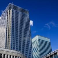 A view from outside a tall office tower, looking upwards, a blue sky is in the background A view from outside a tall office tower, looking upwards, a blue sky is in the background