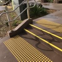 Small external stair way in a primary school with a double handrail on each side, yellow tread nosing strips and yellow tactile ground surface indicators on each landing Small external stair way in a primary school with a double handrail on each side, yellow tread nosing strips and yellow tactile ground surface indicators on each landing