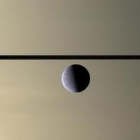 Photograph of Rhea, Saturn's second largest moon, by the Cassini probe. In the back,  the rings and the cloudy atmosphere of the giant planet.   Photograph of Rhea, Saturn's second largest moon, by the Cassini probe. In the back,  the rings and the cloudy atmosphere of the giant planet.