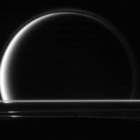 On May 18, 2010, Cassini aimed its camera towards Saturn's largest moon Titan, capturing at the same time the edge of Enceladus (dark region at bottom) and Saturn's rings between the two moons. (NASA/JPL/SSI)