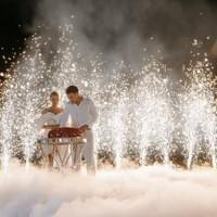 couple découpant leur gateau au milieu de la fumée et et étincelles