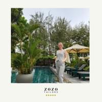 Young woman relaxes at the pool-side terrace of an An Bang beach resort wearing her new bespoke tailored pant suit.