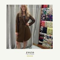 Young professional woman poses in the studio of her An Bang beach tailor wearing the bespoke dress-coat she commissioned