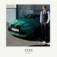 Young man stands in front of green car wearing pinstripe bespoke tailored suit (trousers + wasitcoat) with white shirt.