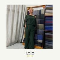 Poised and elegant, the woman is wearing a bespoke tailored resort style pant suit in a silk mix fabric.