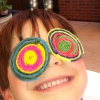 Child with an art project made from colorful "glasses"