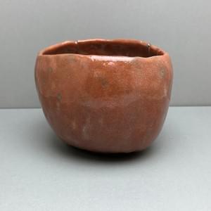 花仙人(加藤長一)作の赤楽茶碗。赤褐色の釉調と手捏ねによる造形 A red Raku tea bowl by Hanasennin (Nagakazu Kato), featuring a reddish-brown glaze and hand-pinched form