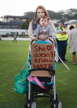 A mother at the Wellington vigil with her child and a sign that says 'She doesn't know hate' A mother at the Wellington vigil with her child and a sign that says 'She doesn't know hate'