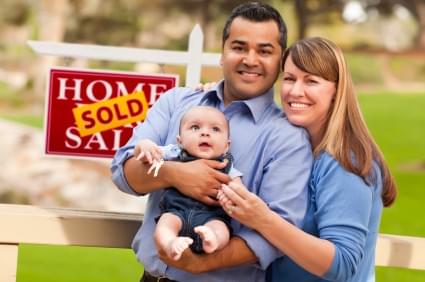 Happy family with SOLD sign in yard Happy family with SOLD sign in yard