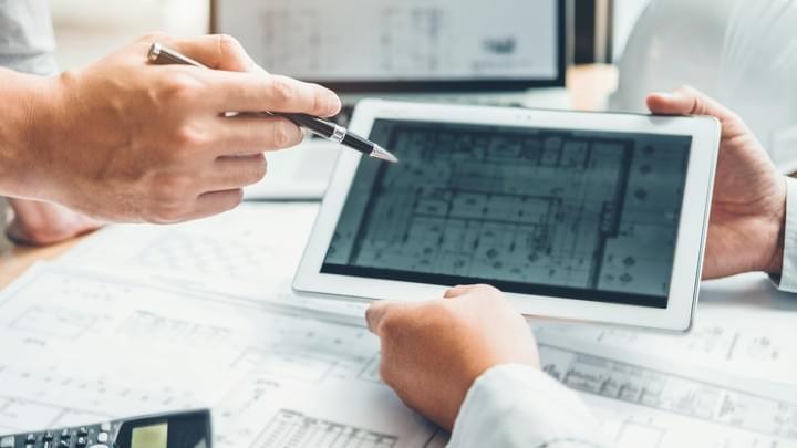 Architectural drawings on a table, rolled out with a ruler across them, and a 3D frame of a large building projecting out of the drawings Architectural drawings on a table, rolled out with a ruler across them, and a 3D frame of a large building projecting out of the drawings