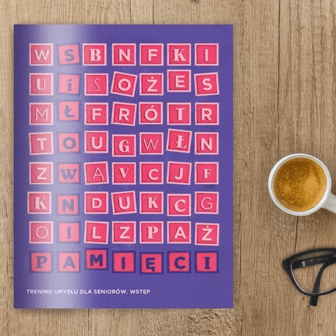Egzemplarz treningu umysłu dla seniorów zawierający wstępne informacje. Obok fioletowej ksiązki leżą okulary i filiżanka kawy. Egzemplarz treningu umysłu dla seniorów zawierający wstępne informacje. Obok fioletowej ksiązki leżą okulary i filiżanka kawy.