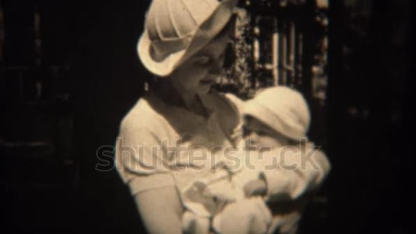 This is a 1930 footage in which a mother holding a newborn baby is dressed in formal outdoor clothes This is a 1930 footage in which a mother holding a newborn baby is dressed in formal outdoor clothes