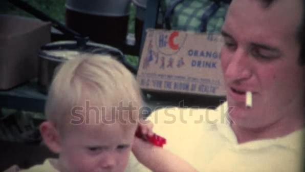 A retro clip of a dad smoking cigarette while cradling a baby. A retro clip of a dad smoking cigarette while cradling a baby.