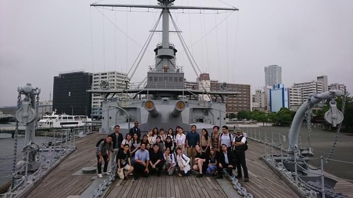 Smiling group of roughly 30 people is gathered for a photo on the deck of the Miskasa museum ship in Yokoksuka Smiling group of roughly 30 people is gathered for a photo on the deck of the Miskasa museum ship in Yokoksuka