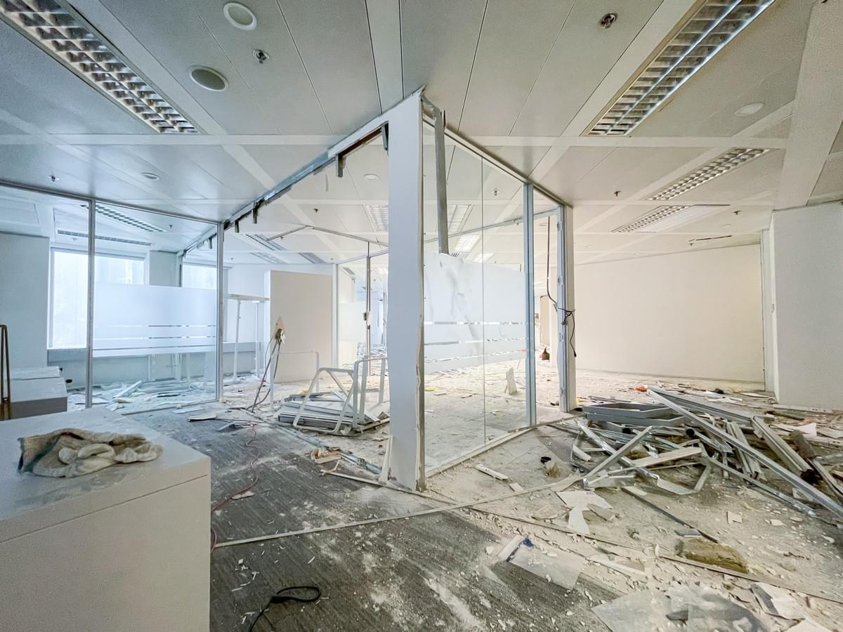 Mid-demolition shot showing glass partitions, exposed ceiling grid and construction debris on floor Mid-demolition shot showing glass partitions, exposed ceiling grid and construction debris on floor