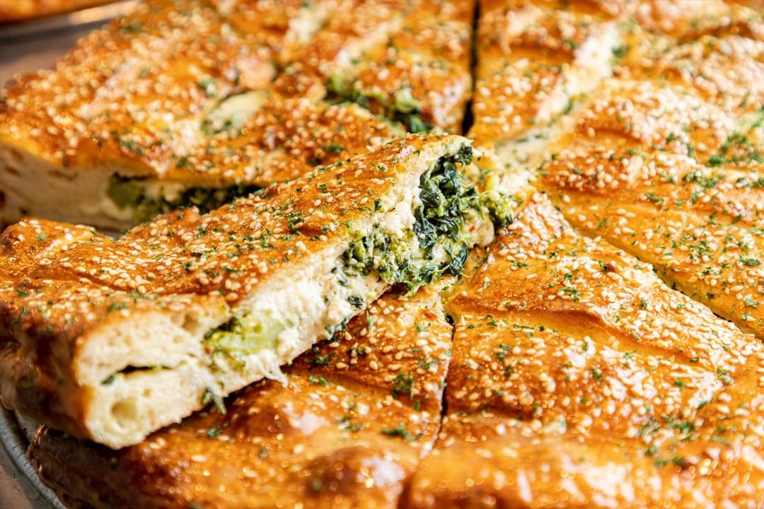 photo of spinach and cheese stuffed whole pizza with slice photo of spinach and cheese stuffed whole pizza with slice