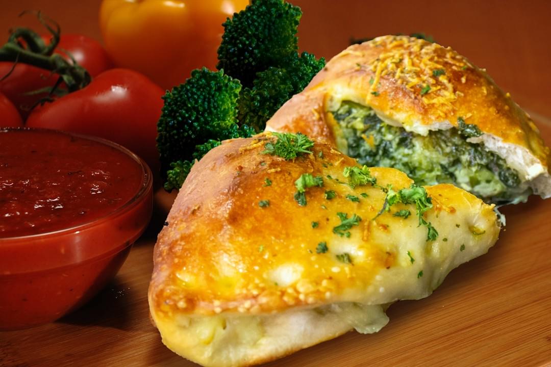 photo of spinach and broccoli calzone with fresh vegetables photo of spinach and broccoli calzone with fresh vegetables