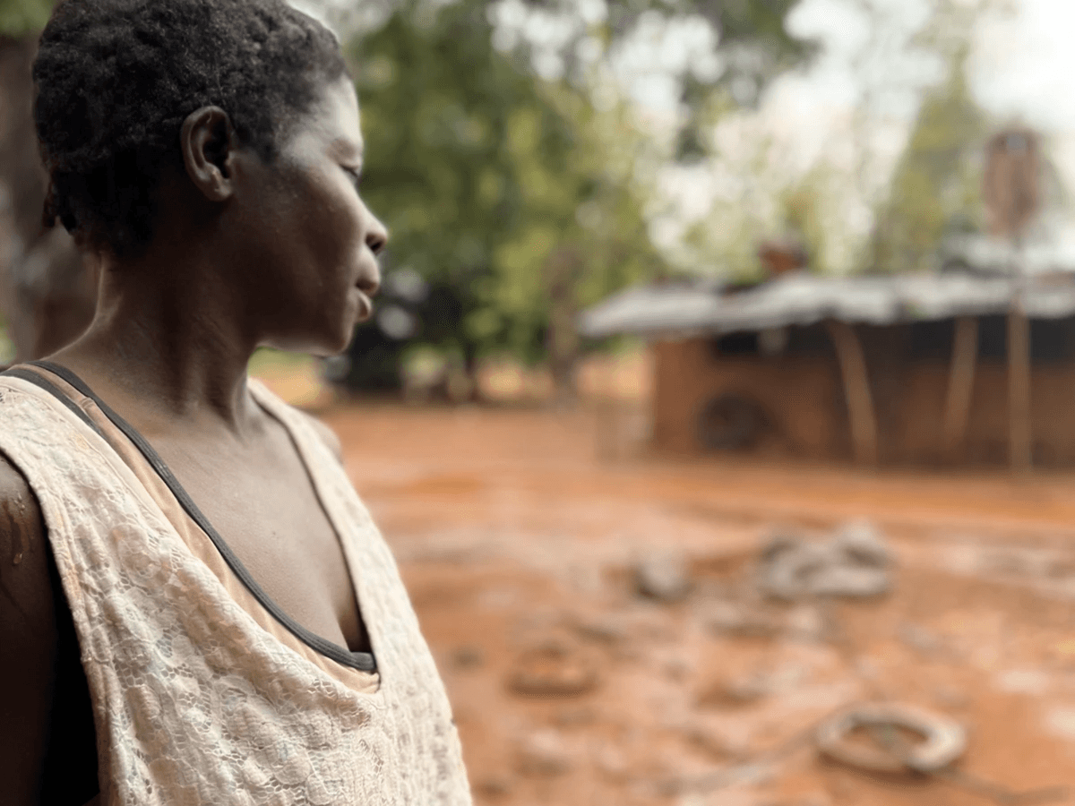 Short haired Zambian woman looking out at a muddy structure  Short haired Zambian woman looking out at a muddy structure
