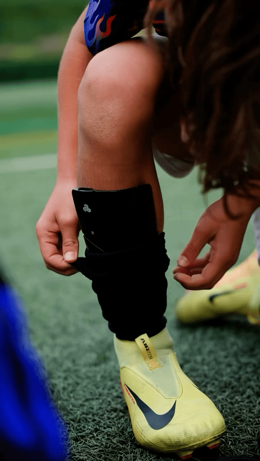 Football player using smart shin guards with integrated smart football trackers for performance tracking. Football player using smart shin guards with integrated smart football trackers for performance tracking.