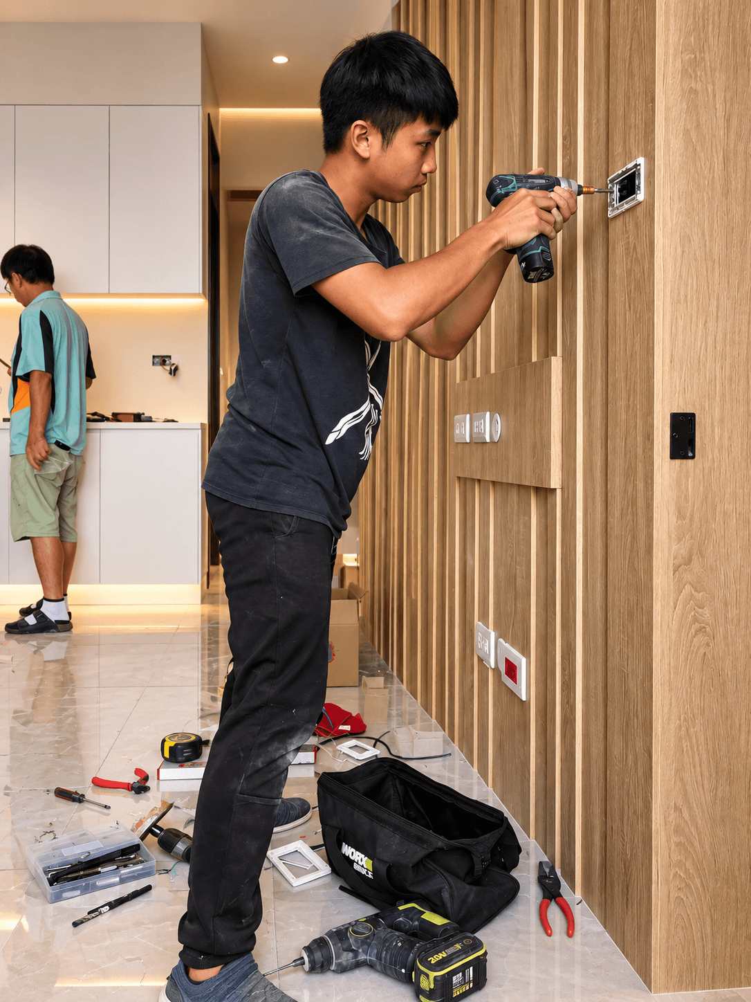 水電師傅在桃園木作造型牆面旁,使用電動螺絲起子精準安裝開關插座面板。 水電師傅在桃園木作造型牆面旁,使用電動螺絲起子精準安裝開關插座面板。