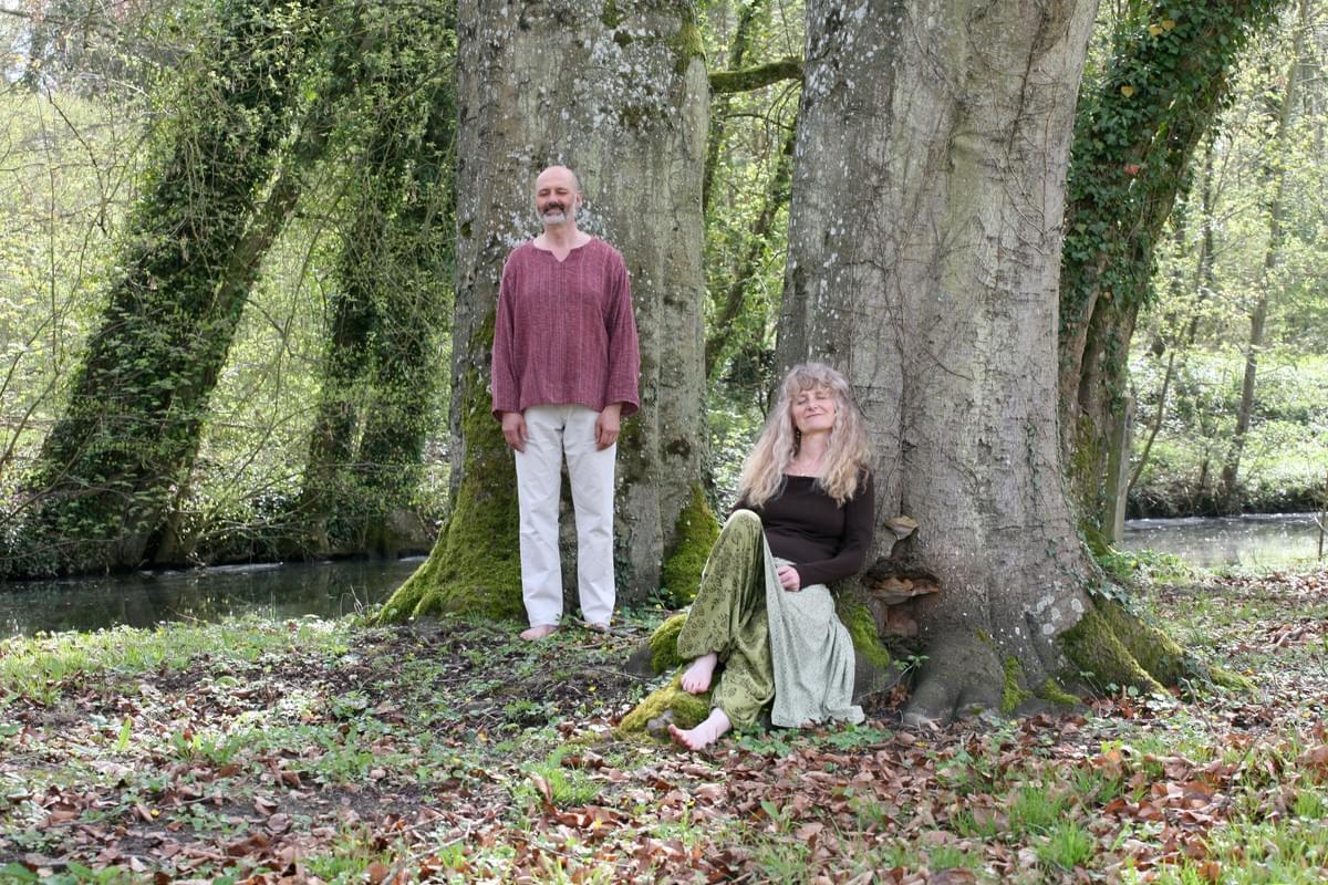 Nathalie et Jean-Luc Champougny, chacun devant un arbre, en pleine méditation, avec un cours d'eau qui passe derrière eux Nathalie et Jean-Luc Champougny, chacun devant un arbre, en pleine méditation, avec un cours d'eau qui passe derrière eux