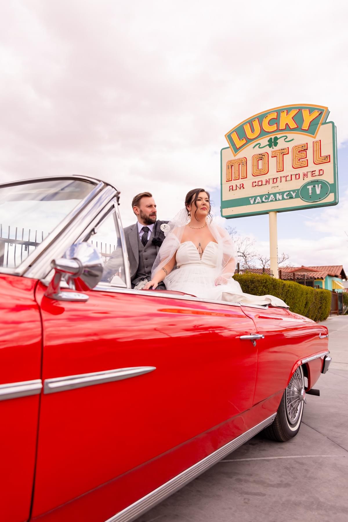Couple posing next to a red Cadillac on Fremont Street in Las Vegas as part of their Drive Thru wedding experience at Sure Thing Chapel. Couple posing next to a red Cadillac on Fremont Street in Las Vegas as part of their Drive Thru wedding experience at Sure Thing Chapel.