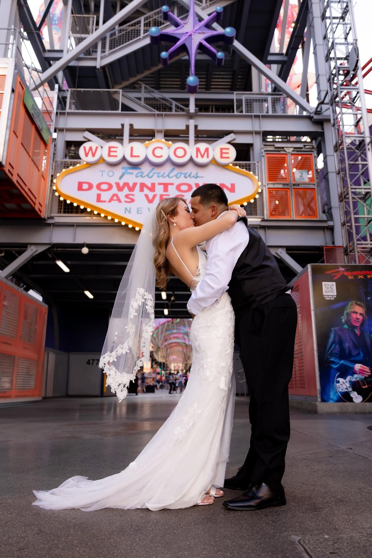 Couple sharing a kiss in front of the iconic Welcome to Las Vegas sign on Fremont Street during their same-day elopement. Couple sharing a kiss in front of the iconic Welcome to Las Vegas sign on Fremont Street during their same-day elopement.