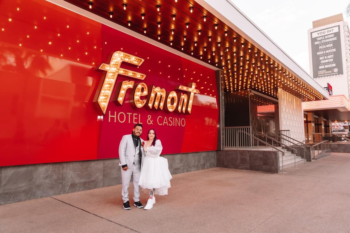 Couple posing in front of the Fremont Hotel on Fremont Street, capturing the vintage Las Vegas neon vibe. Couple posing in front of the Fremont Hotel on Fremont Street, capturing the vintage Las Vegas neon vibe.