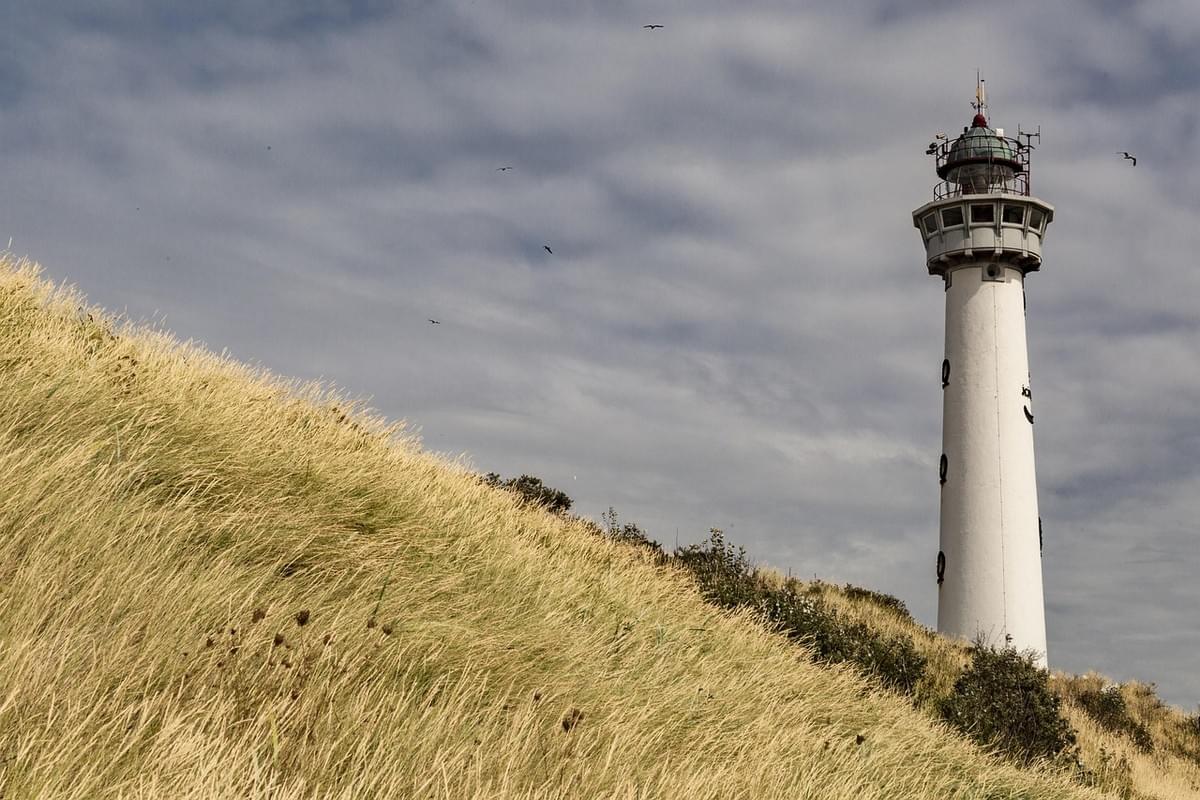 A lighthouse on a hill against a cloudy blue sky A lighthouse on a hill against a cloudy blue sky
