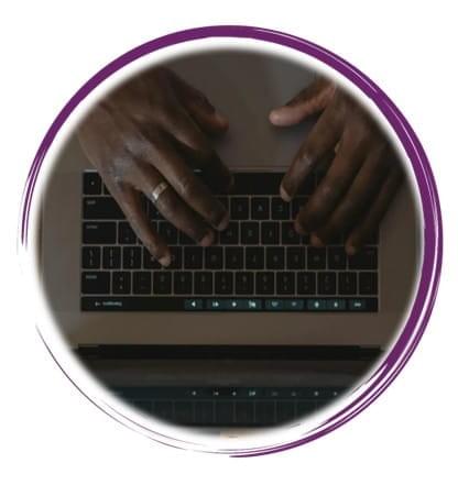 A top-down close-up view of a person actively using a laptop, likely a MacBook, identifiable by its keyboard layout and touch bar. The individual’s hands rest on the keyboard in a poised typing position, suggesting engagement with work, study, or communication. The screen reflects the keyboard and hands, adding depth and symmetry to the composition. The person wears a ring on their left hand and torn black jeans, introducing subtle personal style elements. The setting appears casual and modern, with the chair and posture indicating a focused yet relaxed digital interaction. The image captures a moment of contemporary tech use, emphasizing themes of productivity, individuality, and the tactile nature of digital engagement A top-down close-up view of a person actively using a laptop, likely a MacBook, identifiable by its keyboard layout and touch bar. The individual’s hands rest on the keyboard in a poised typing position, suggesting engagement with work, study, or communication. The screen reflects the keyboard and hands, adding depth and symmetry to the composition. The person wears a ring on their left hand and torn black jeans, introducing subtle personal style elements. The setting appears casual and modern, with the chair and posture indicating a focused yet relaxed digital interaction. The image captures a moment of contemporary tech use, emphasizing themes of productivity, individuality, and the tactile nature of digital engagement