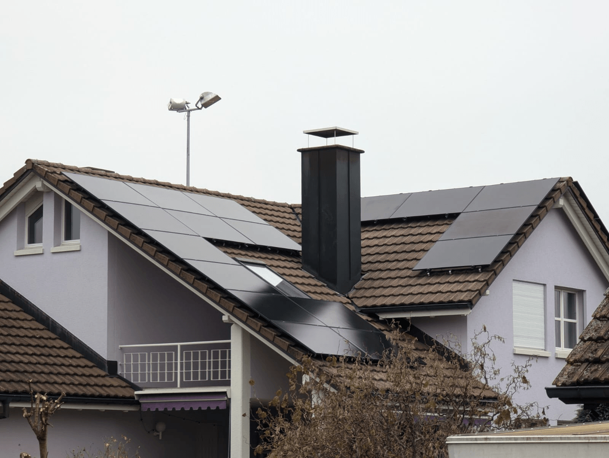 Widok instalacji modułów fotowoltaicznych full black na dachu domu jednorodzinnego, panel TOPCon 450W – połączenie estetyki i wysokiej wydajności. Widok instalacji modułów fotowoltaicznych full black na dachu domu jednorodzinnego, panel TOPCon 450W – połączenie estetyki i wysokiej wydajności.