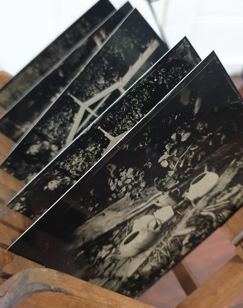a wooden rack holds five photographs taken in thin sheets of tin a wooden rack holds five photographs taken in thin sheets of tin