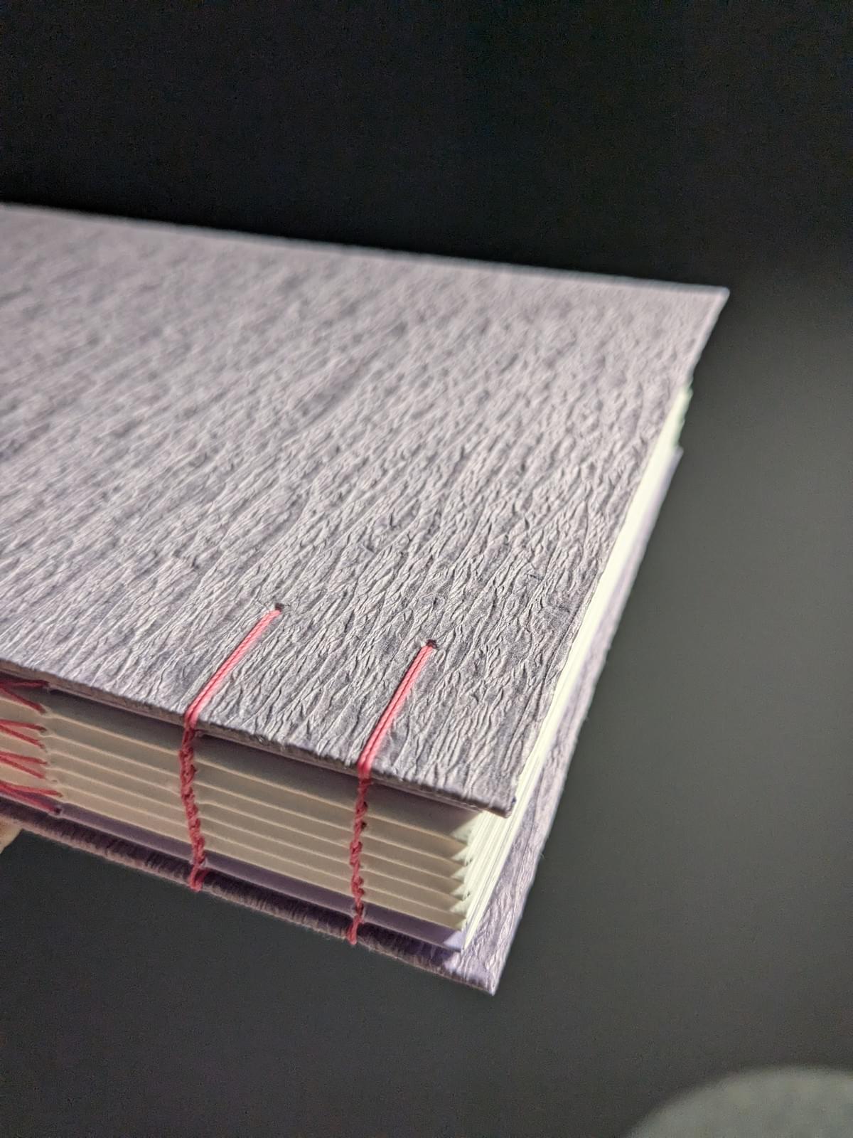 book binding - purple textured cover with coptic stitch in pink thread book binding - purple textured cover with coptic stitch in pink thread