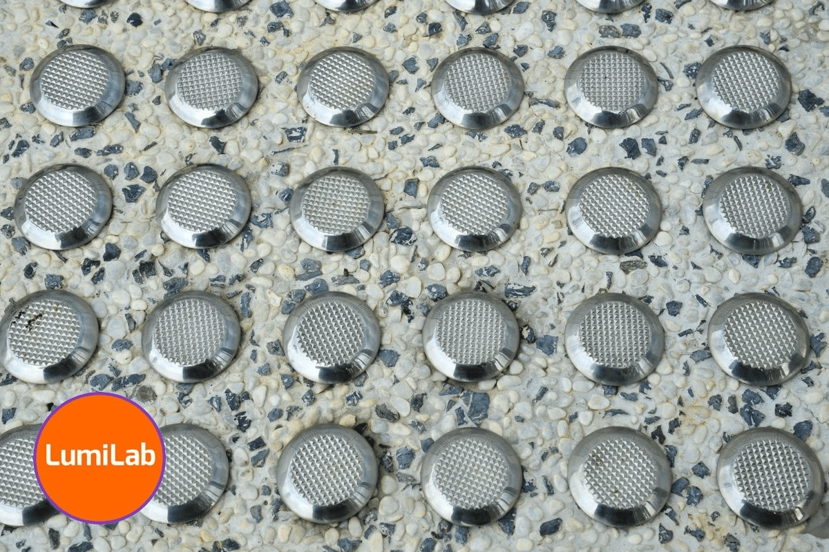 Close-up image of Tactile Ground Surface Indicators on a pebble-textured flooring Close-up image of Tactile Ground Surface Indicators on a pebble-textured flooring