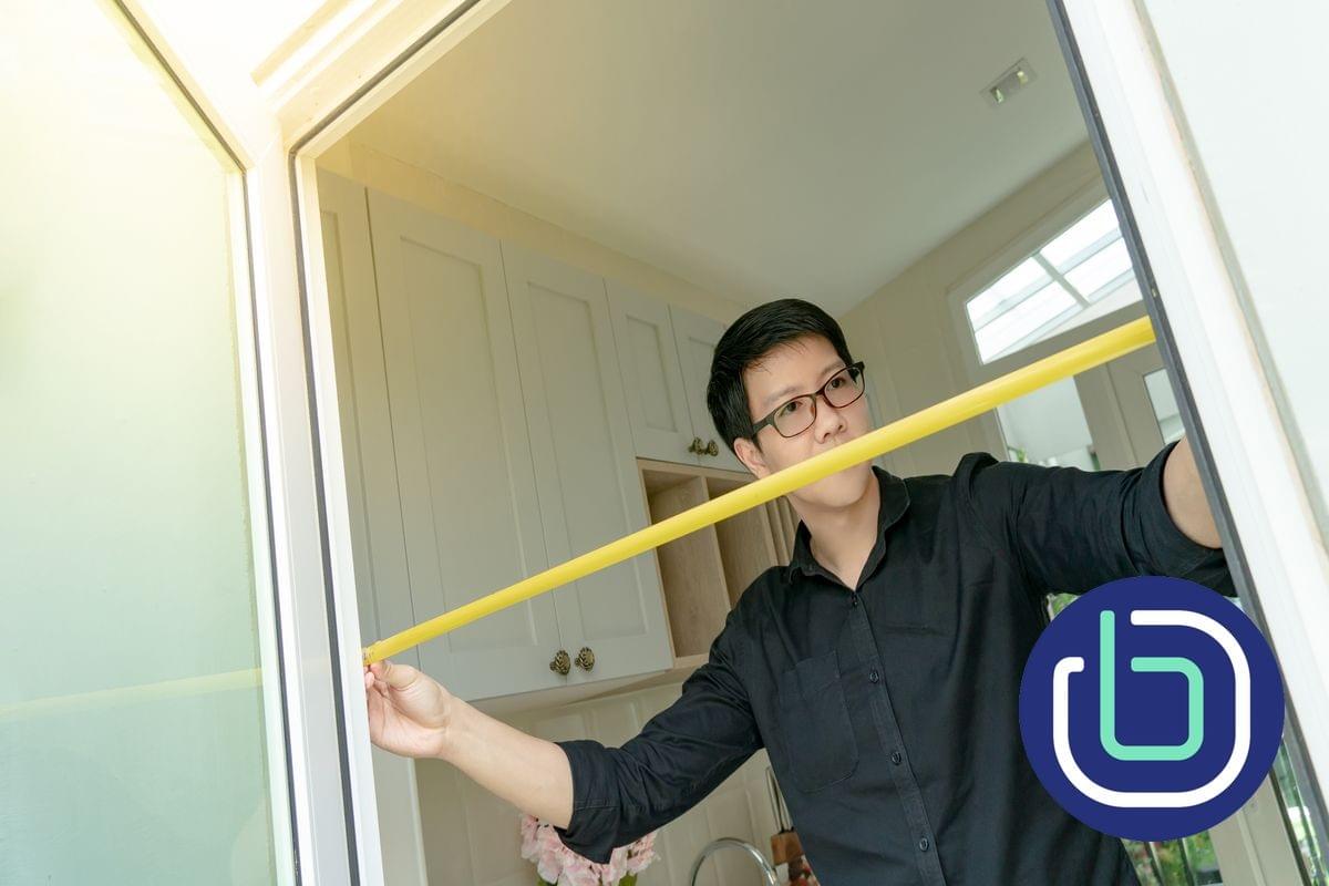 A male access consultant is measuring the clearance in a door opening A male access consultant is measuring the clearance in a door opening