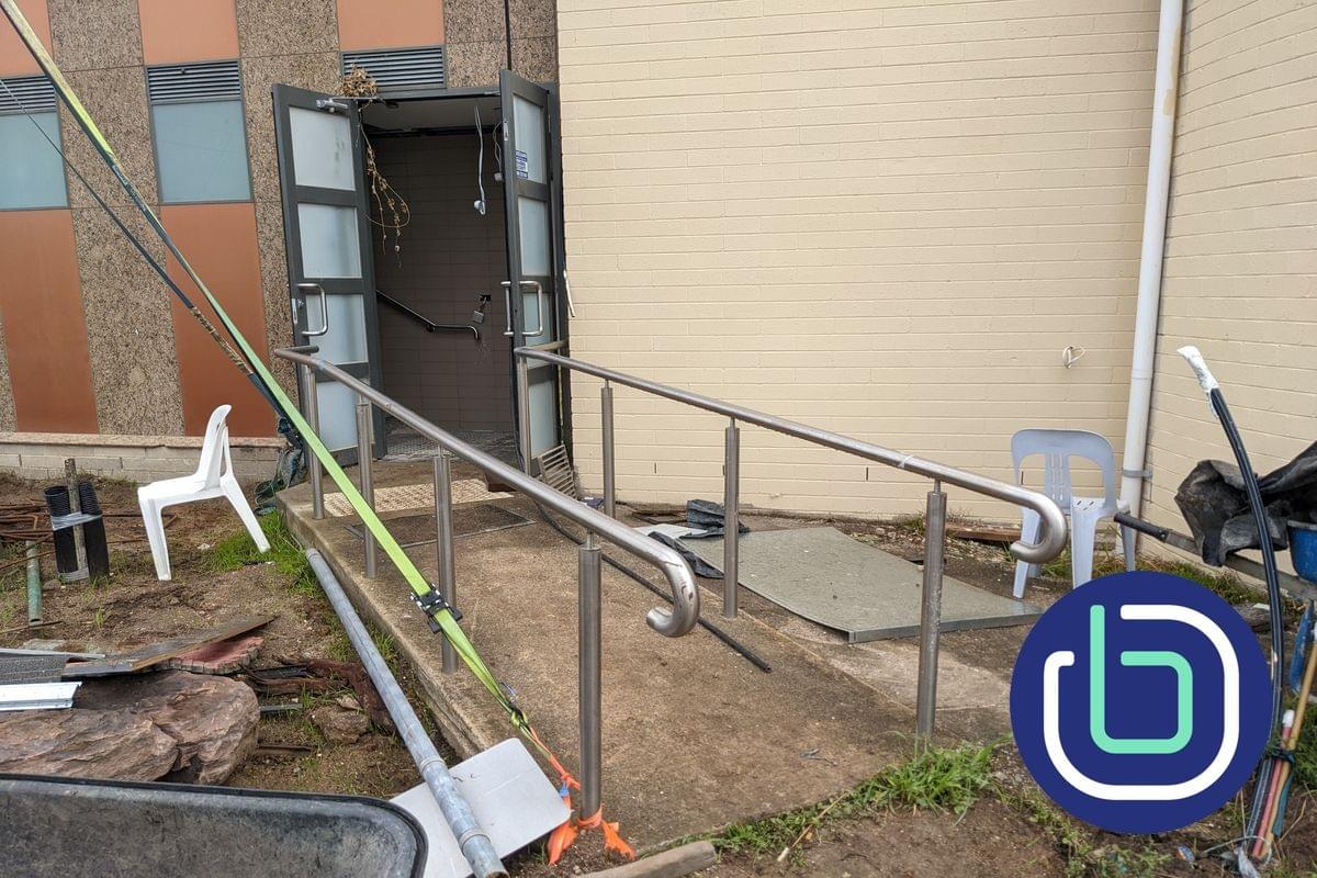 A concrete ramp and stainless steel handrails leading to a building entrance A concrete ramp and stainless steel handrails leading to a building entrance