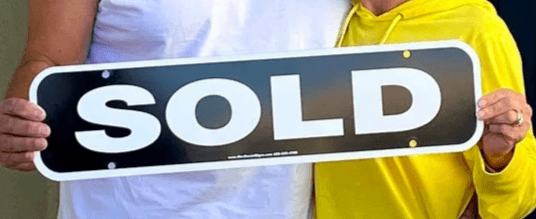 Real Estate Sold Sign held by couple Real Estate Sold Sign held by couple