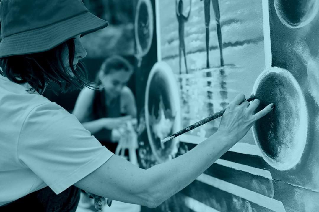 Artist painting custom mural on interior feature wall in modern studio Artist painting custom mural on interior feature wall in modern studio