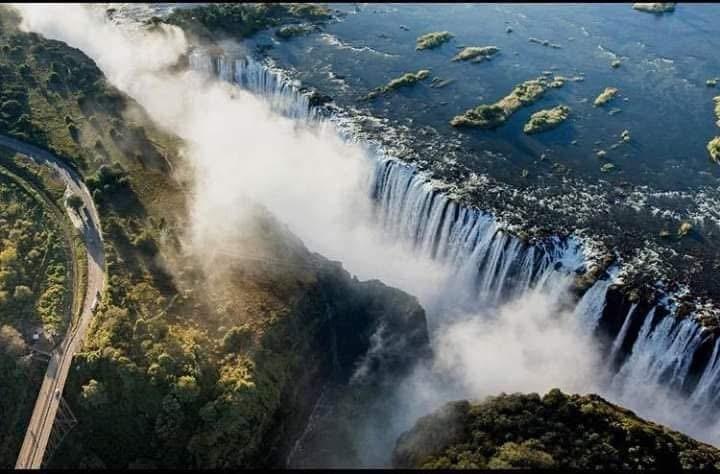 Aerial view of the Zambezi River flowing into the dramatic Victoria Falls, with the mist rising from the waterfall. Aerial view of the Zambezi River flowing into the dramatic Victoria Falls, with the mist rising from the waterfall.
