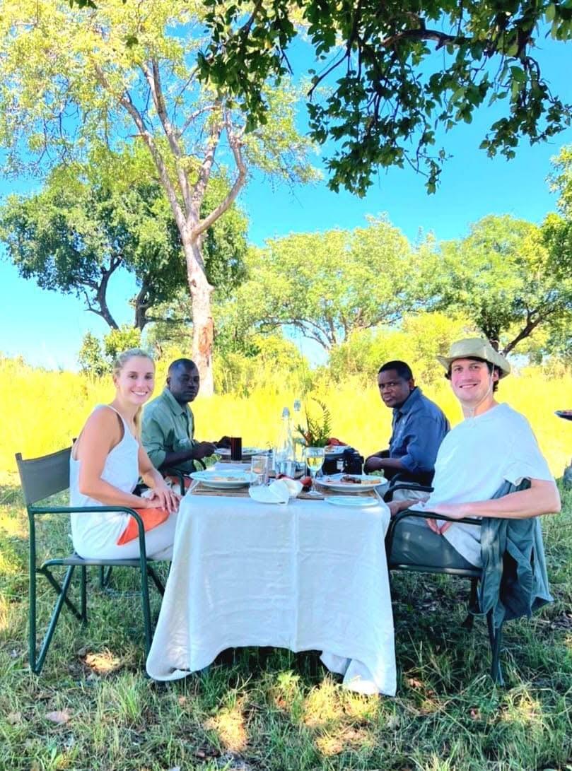 A group of people enjoying an outdoor lunch surrounded by nature. A group of people enjoying an outdoor lunch surrounded by nature.