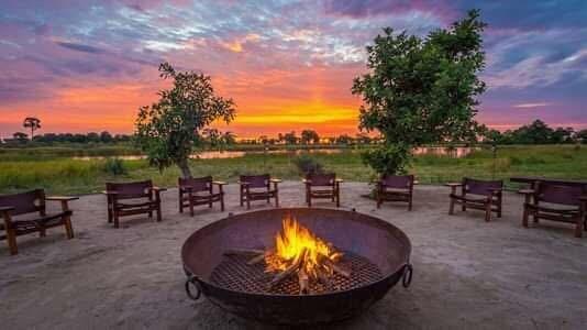 Camp chairs neatly arranged a fire pit, with a breathtaking sunset casting warm hues over the landscape. Camp chairs neatly arranged a fire pit, with a breathtaking sunset casting warm hues over the landscape.