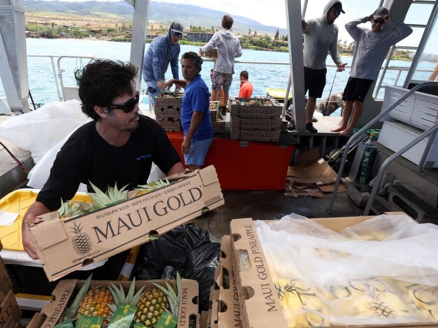 Volunteers stack boxes of pineapple that will be transferred to shore by a small boat on Aug. 14, 2023, in Kaanapali, Hawaii. Volunteers stack boxes of pineapple that will be transferred to shore by a small boat on Aug. 14, 2023, in Kaanapali, Hawaii.