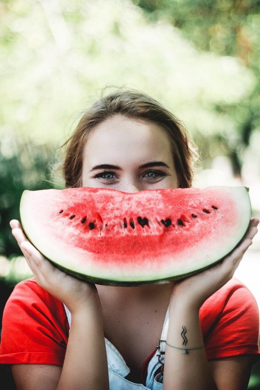 A photo of a girl holding a cut watermelon in front of her face to look like a smile, as featured in the blog post "Tips for Plant-Based-Diet Veterans" on The Purple Dog Blog by The Purple Dog Vegan A photo of a girl holding a cut watermelon in front of her face to look like a smile, as featured in the blog post "Tips for Plant-Based-Diet Veterans" on The Purple Dog Blog by The Purple Dog Vegan