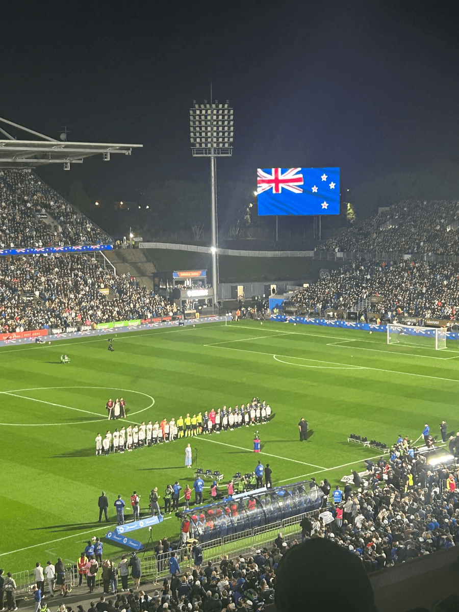 Photo of Mt Smart Stadium with soccer teams ready to play and NZ flag on screen. Photo of Mt Smart Stadium with soccer teams ready to play and NZ flag on screen.