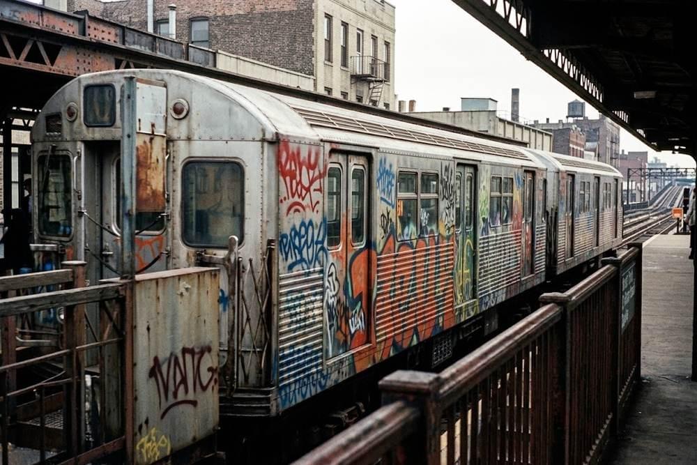 Rame de métro des années 1970 couverte de peintures aérosol colorées le long d'un quai aérien Rame de métro des années 1970 couverte de peintures aérosol colorées le long d'un quai aérien