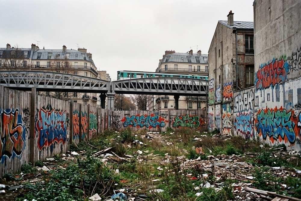 Terrain vague parisien des années 1980 aux murs peints, viaduc de métro aérien en arrière-plan Terrain vague parisien des années 1980 aux murs peints, viaduc de métro aérien en arrière-plan