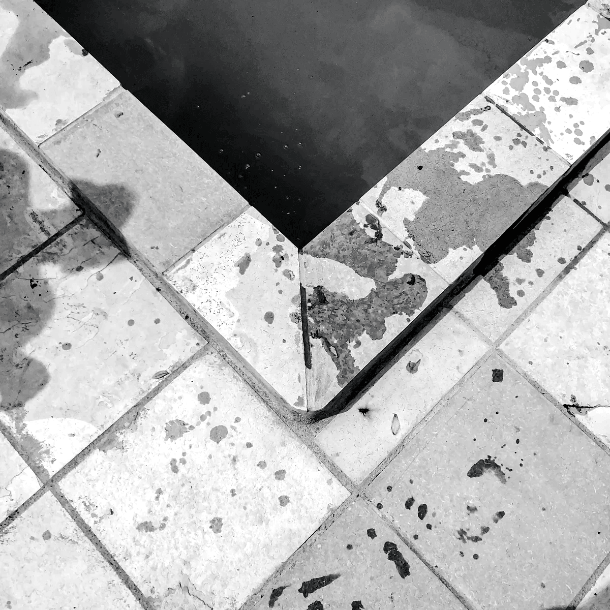 A black and white swimming pool surrounded by stone tiling A black and white swimming pool surrounded by stone tiling