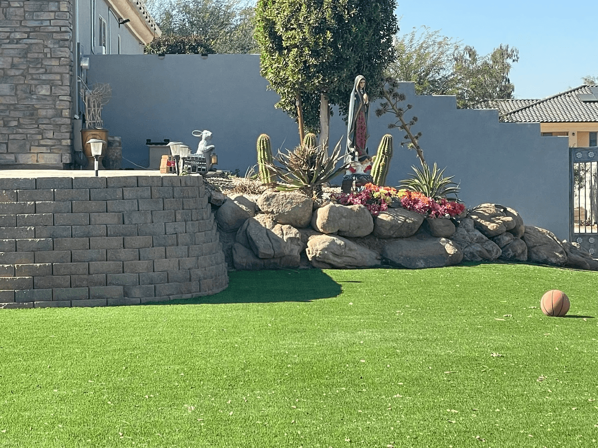 Beautiful retaining wall with stone and cactus garden, artificial grass and stone work with a deocrative block wall in the background in Avondale neighborhood Beautiful retaining wall with stone and cactus garden, artificial grass and stone work with a deocrative block wall in the background in Avondale neighborhood