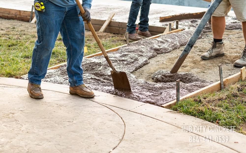 crew spreading wet concrete in form for new addition around pool deck crew spreading wet concrete in form for new addition around pool deck