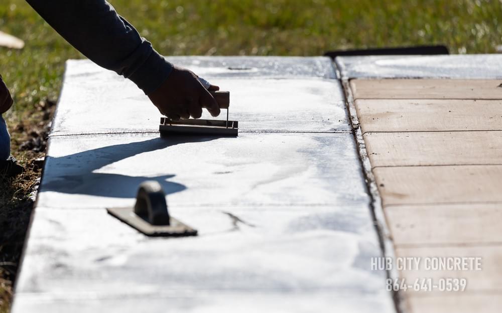 worker creating control joint by hand trowel in decorative concrete border worker creating control joint by hand trowel in decorative concrete border